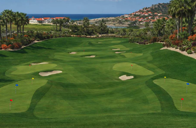 One&Only Palmilla Golf Club practice range with target greens, bunkers, palm trees, and views toward the Sea of Cortez.